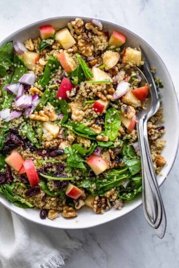 Walnut apple quinoa salad serve in a large bowl with utensils