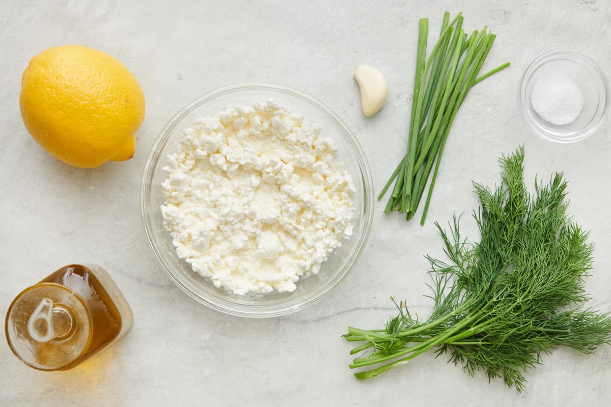 Ingredients for dip recipe: lemon, oil, cottage cheese, garlic, chives, dill, and salt.